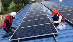 Men installing a solar panel on a roof in Cambodia