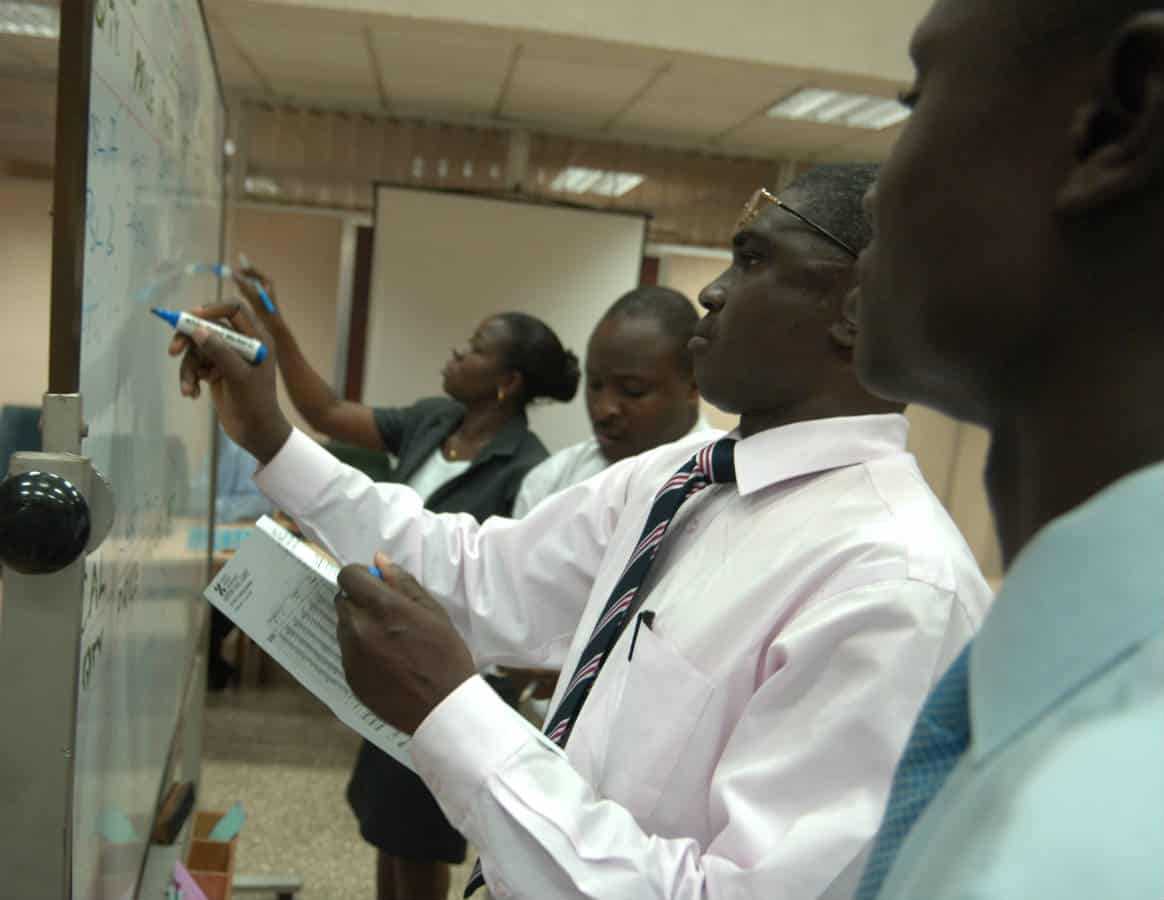 College students writing on a whiteboard in Ghana