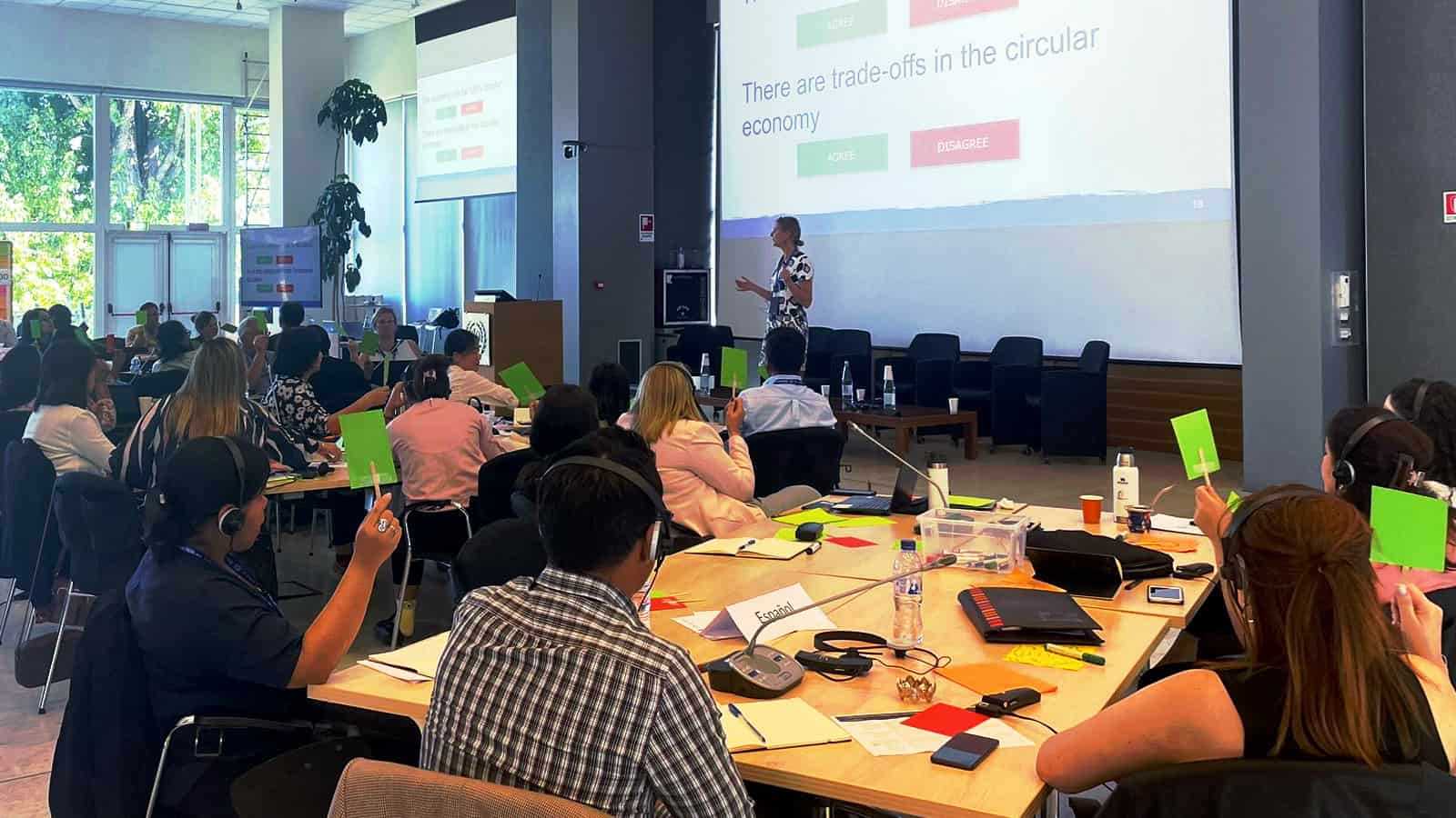 A group of people in a workshop watching a screen and listening to a moderator during the Green Economy Academy in Turin held in 2023.