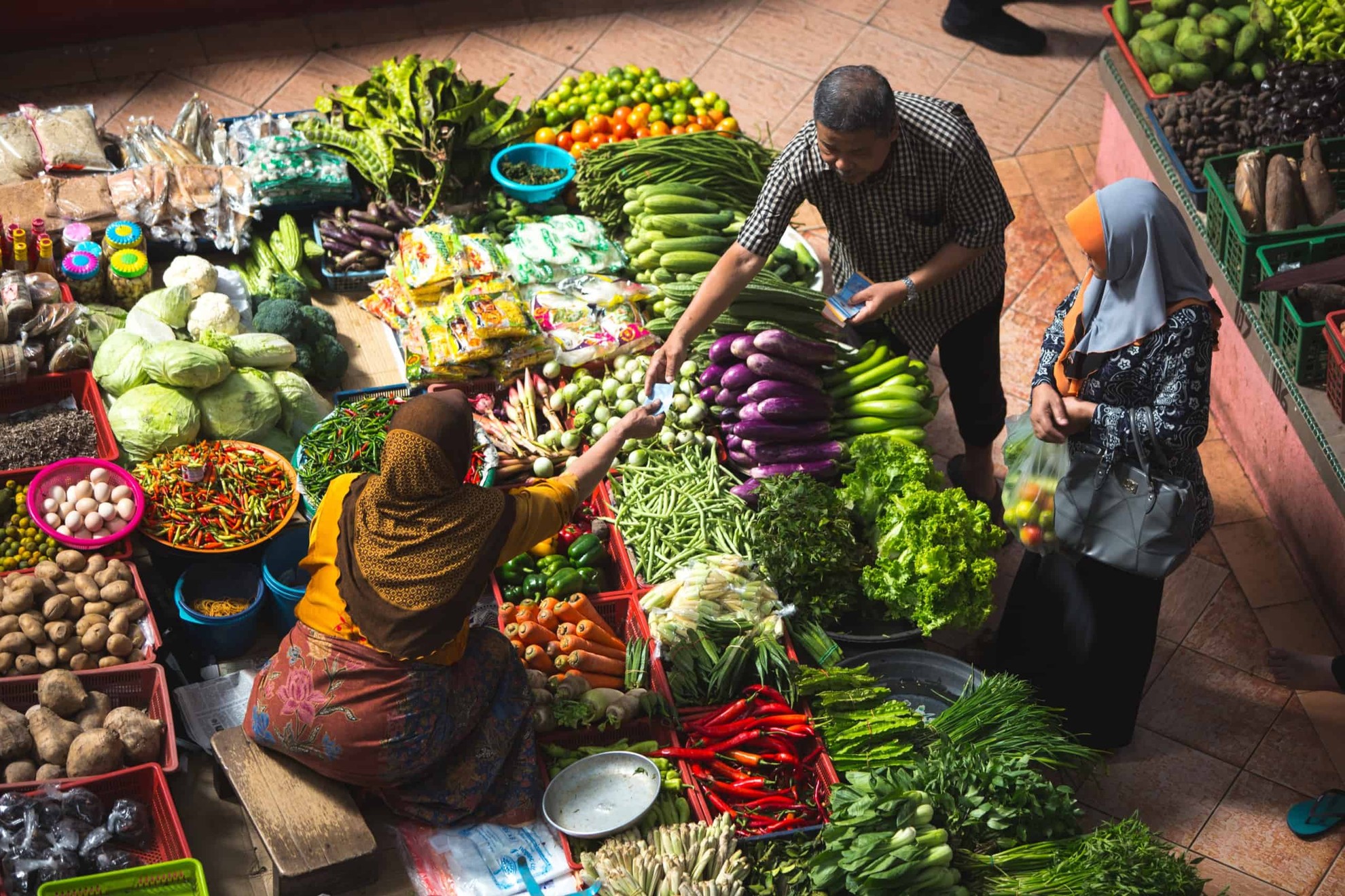 Produce vendor and shoppers at a market in Indonesia